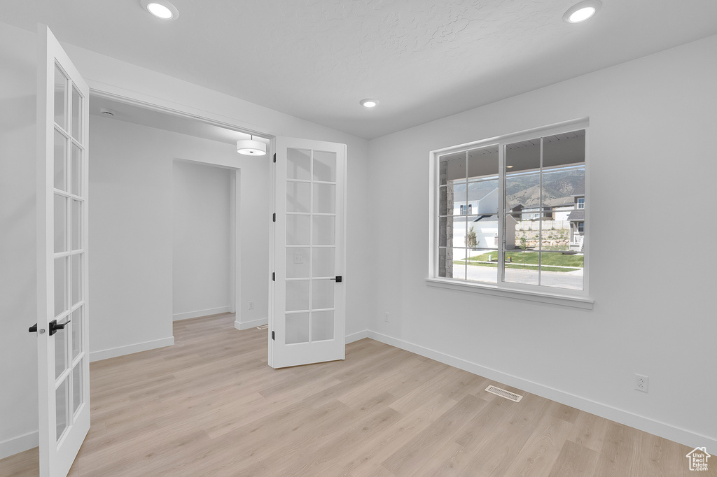 Unfurnished room with french doors, light wood-style floors, baseboards, and recessed lighting