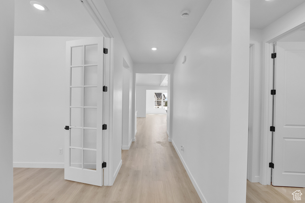 Hallway with light wood finished floors, recessed lighting, and baseboards