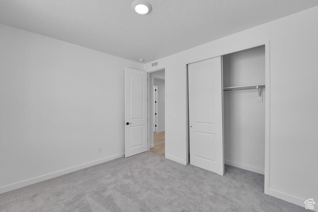 Unfurnished bedroom featuring carpet floors, baseboards, and a closet