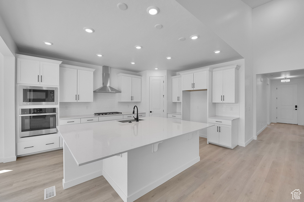 Kitchen featuring oven, wall chimney range hood, a sink, built in microwave, and recessed lighting