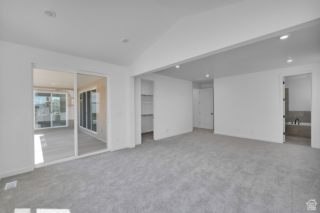 Unfurnished bedroom featuring carpet, lofted ceiling, a spacious closet, baseboards, and recessed lighting