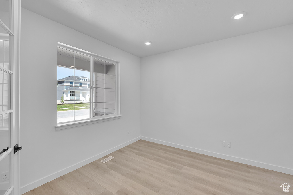 Empty room featuring light wood-style flooring, baseboards, and recessed lighting