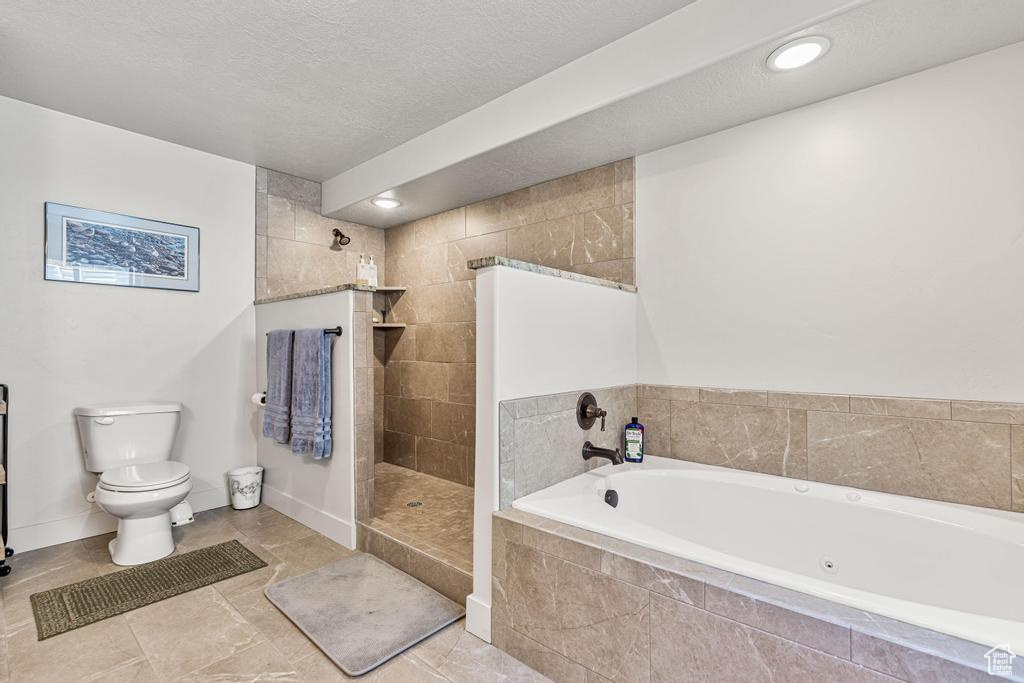 Bathroom featuring a jetted tub, toilet, walk in shower, tile patterned flooring, and baseboards