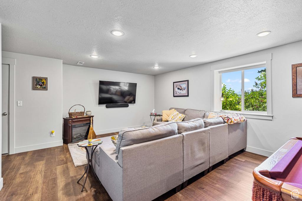 Living area featuring wood finished floors, a textured ceiling, recessed lighting, baseboards, and a fireplace