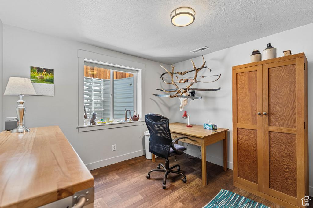 Office area with a textured ceiling, wood finished floors, and baseboards