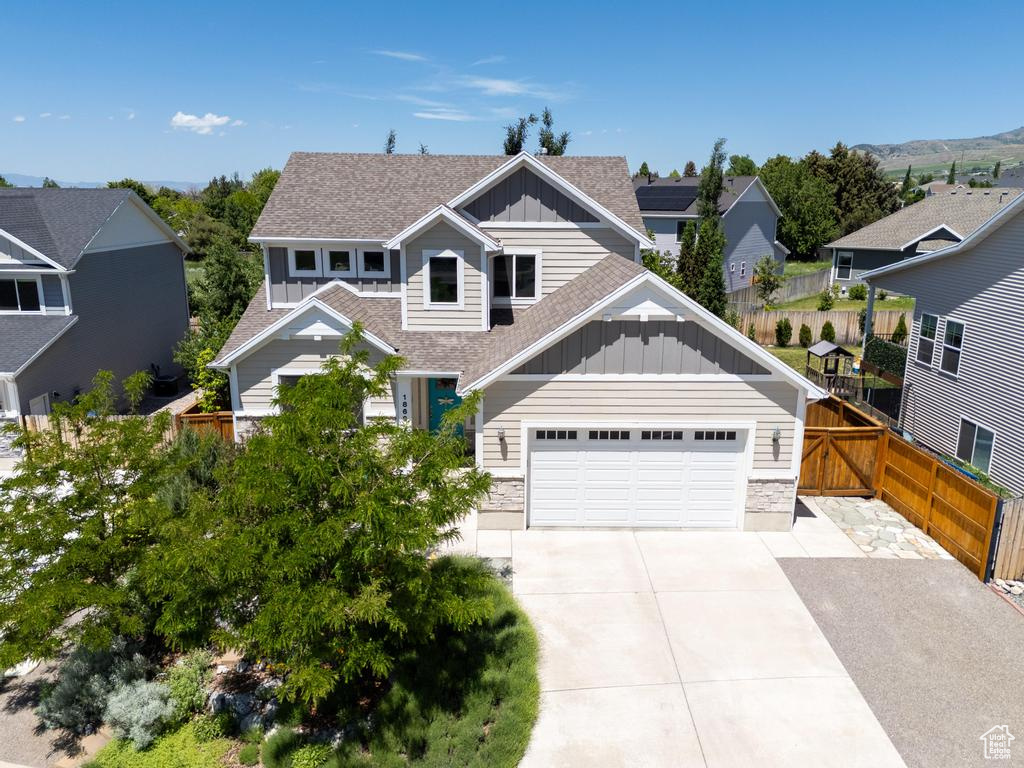 Craftsman-style house featuring board and batten siding, a shingled roof, concrete driveway, and an attached garage