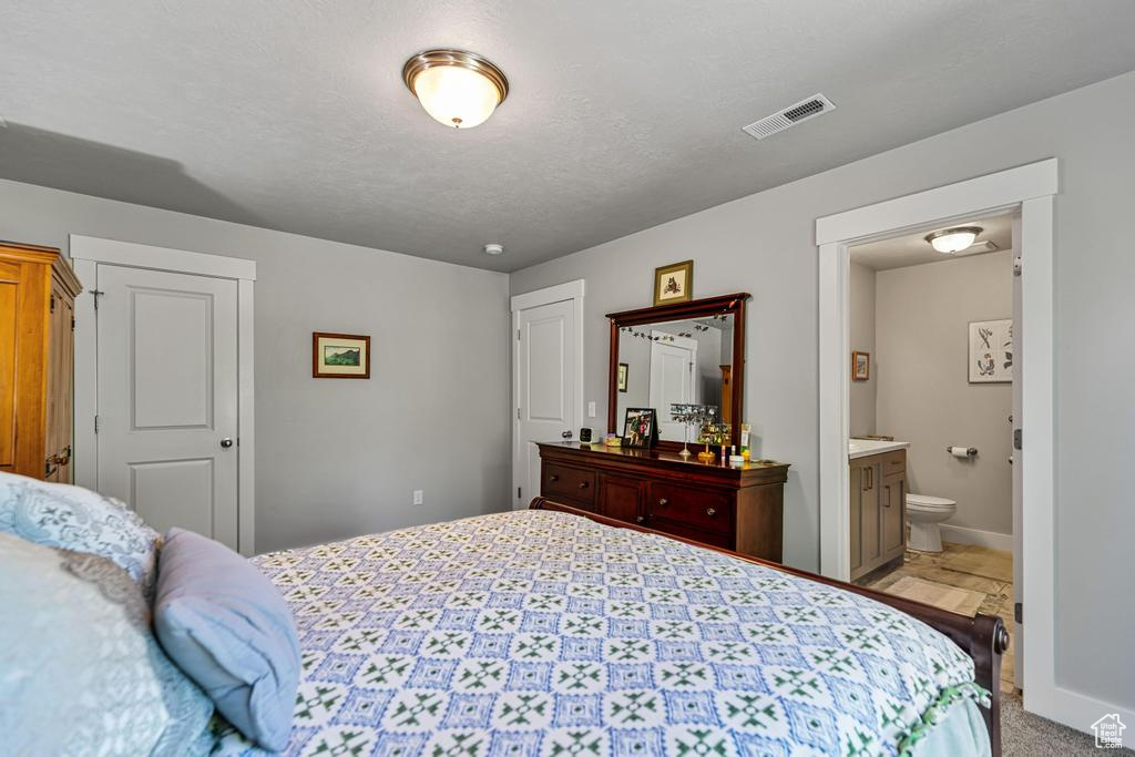 Bedroom featuring baseboards, ensuite bathroom, and light carpet