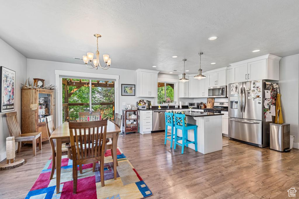 Dining room featuring a chandelier, recessed lighting, light wood-type flooring, and a textured ceiling