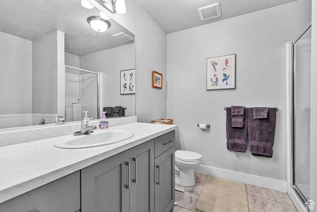 Full bath featuring vanity, a shower stall, toilet, and baseboards