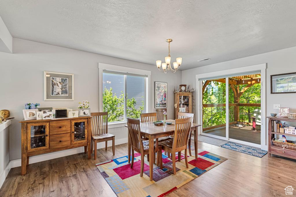 Dining room with wood finished floors, a chandelier, a textured ceiling, and baseboards