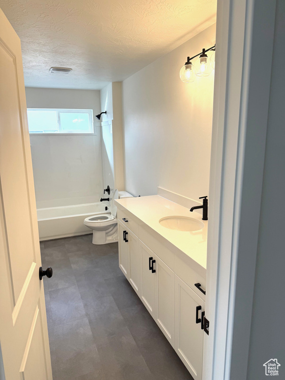 Full bathroom with a textured ceiling, toilet, shower / bath combination, and vanity