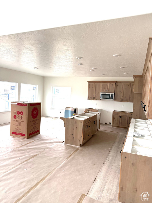 Kitchen featuring stainless steel microwave and a textured ceiling