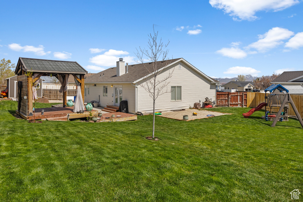 Back of house featuring a yard, a fenced backyard, and a playground