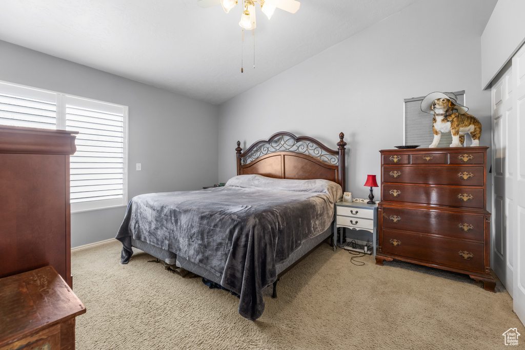 Bedroom with a closet, ceiling fan, light colored carpet, and lofted ceiling