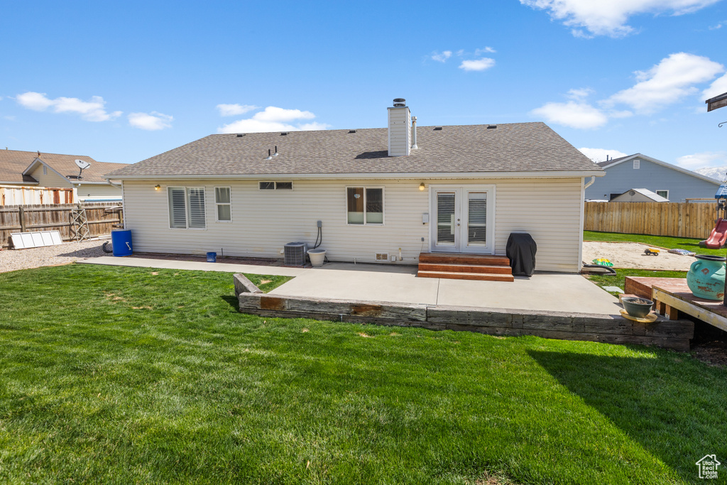 Rear view of house featuring a fenced backyard, a lawn, a patio area, french doors, and central AC unit