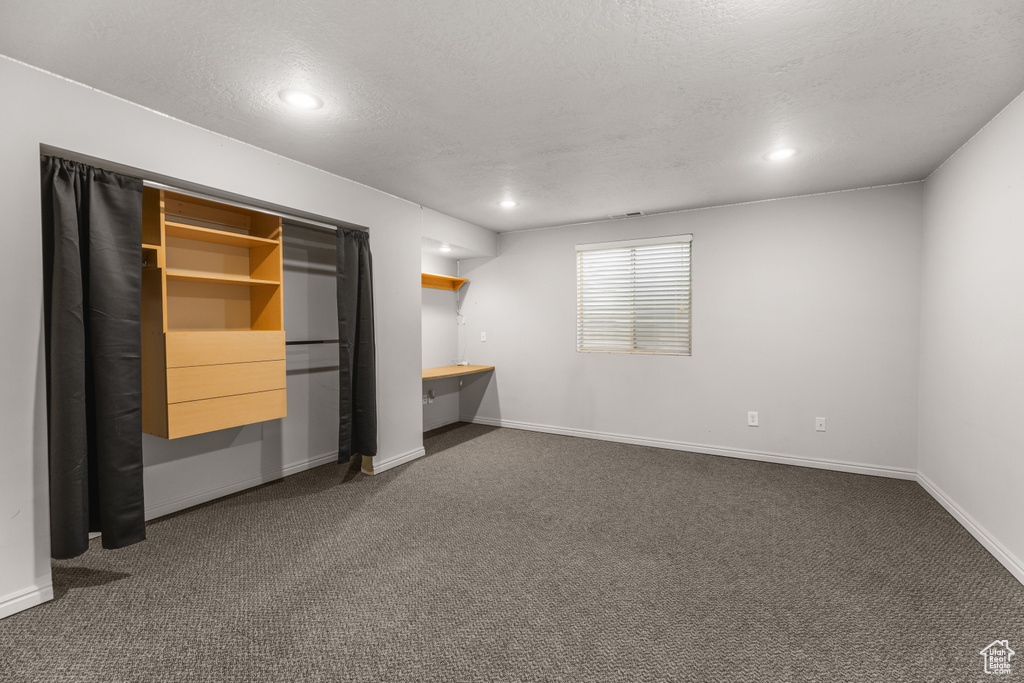Unfurnished bedroom featuring baseboards, recessed lighting, dark colored carpet, and a textured ceiling