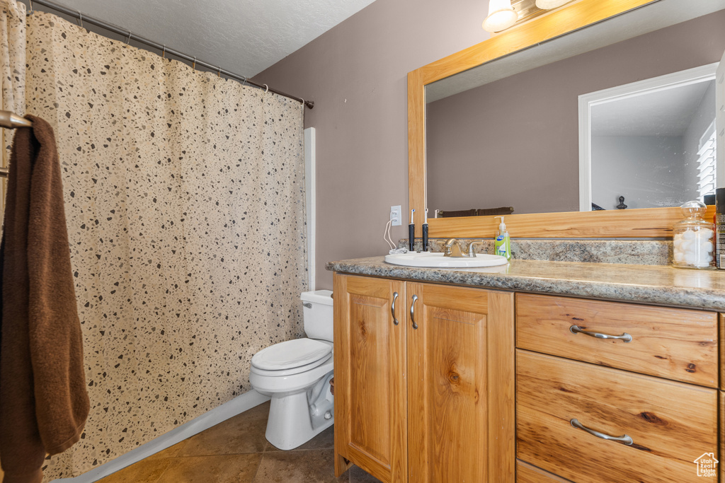 Full bath with toilet, tile patterned floors, vanity, and a shower with shower curtain