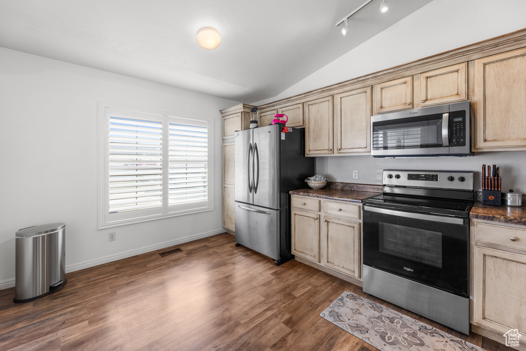 Kitchen with visible vents, dark countertops, lofted ceiling, stainless steel appliances, and light brown cabinets
