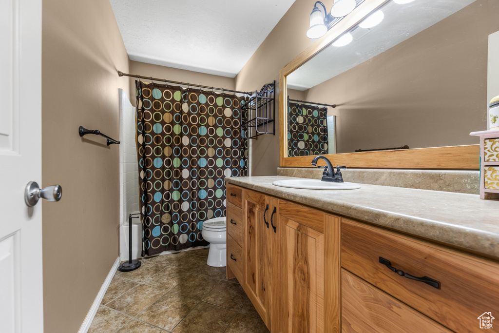 Full bath featuring toilet, tile patterned floors, vanity, and baseboards