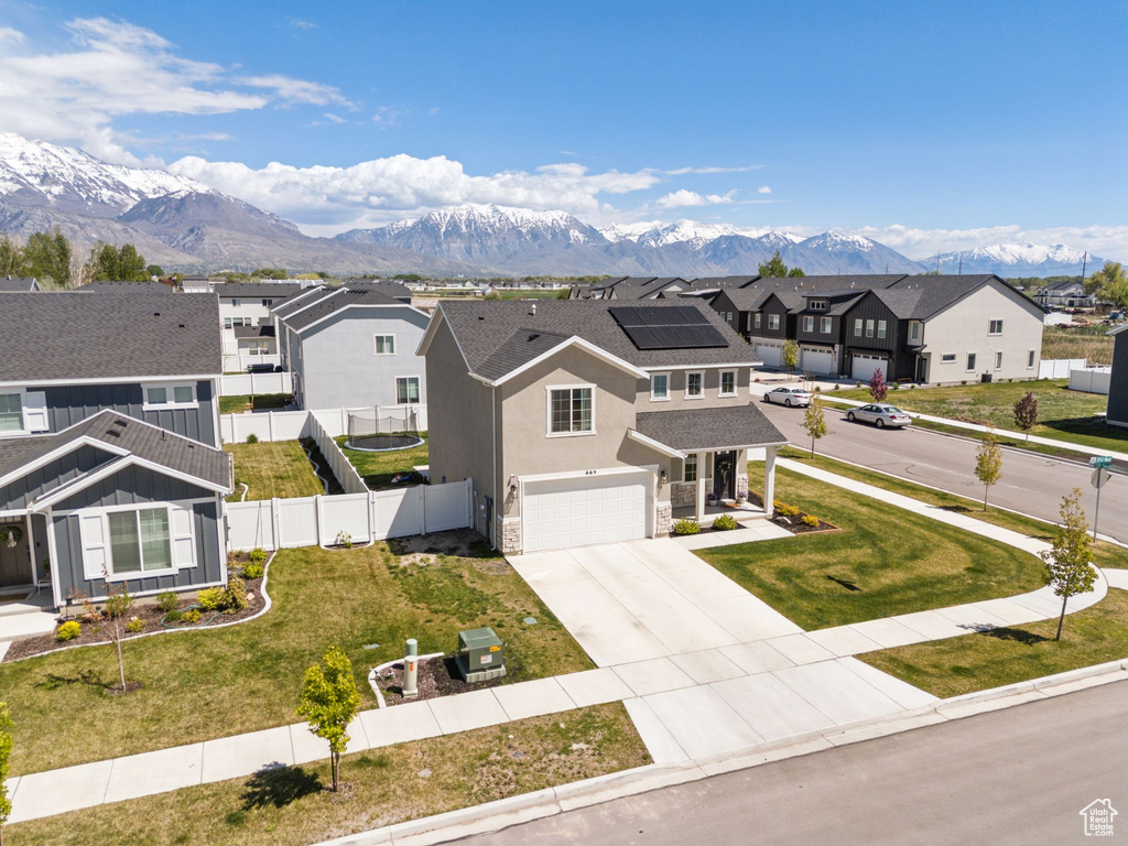 View of front of property featuring concrete driveway, a residential view, a mountain view, and a garage