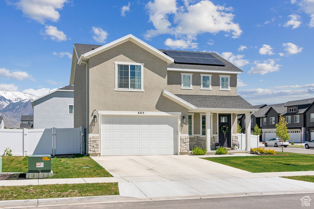 View of front facade featuring fence, solar panels, a gate, and stucco siding