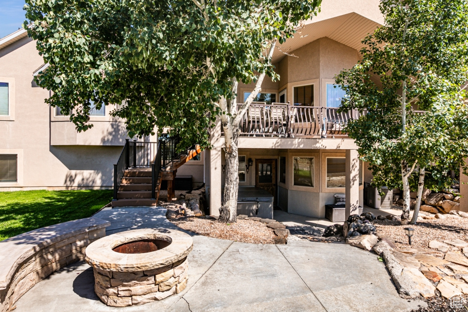 Back of property featuring an outdoor fire pit, stucco siding, stairway, and a patio