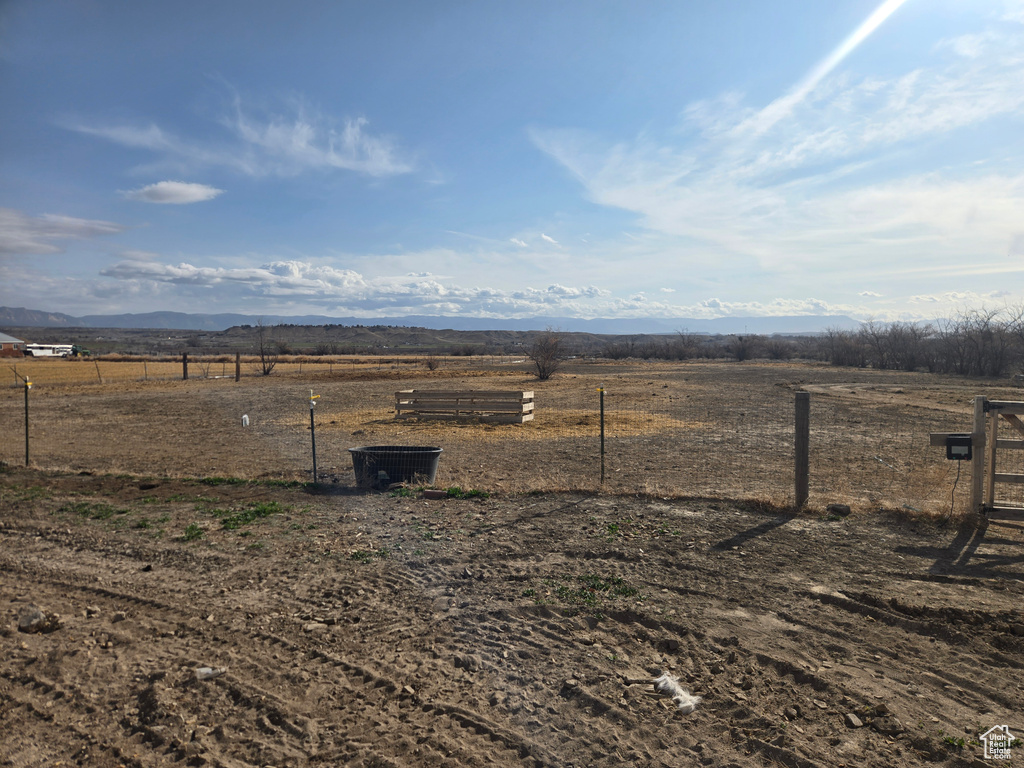View of yard with fence, a rural view, and a mountain view