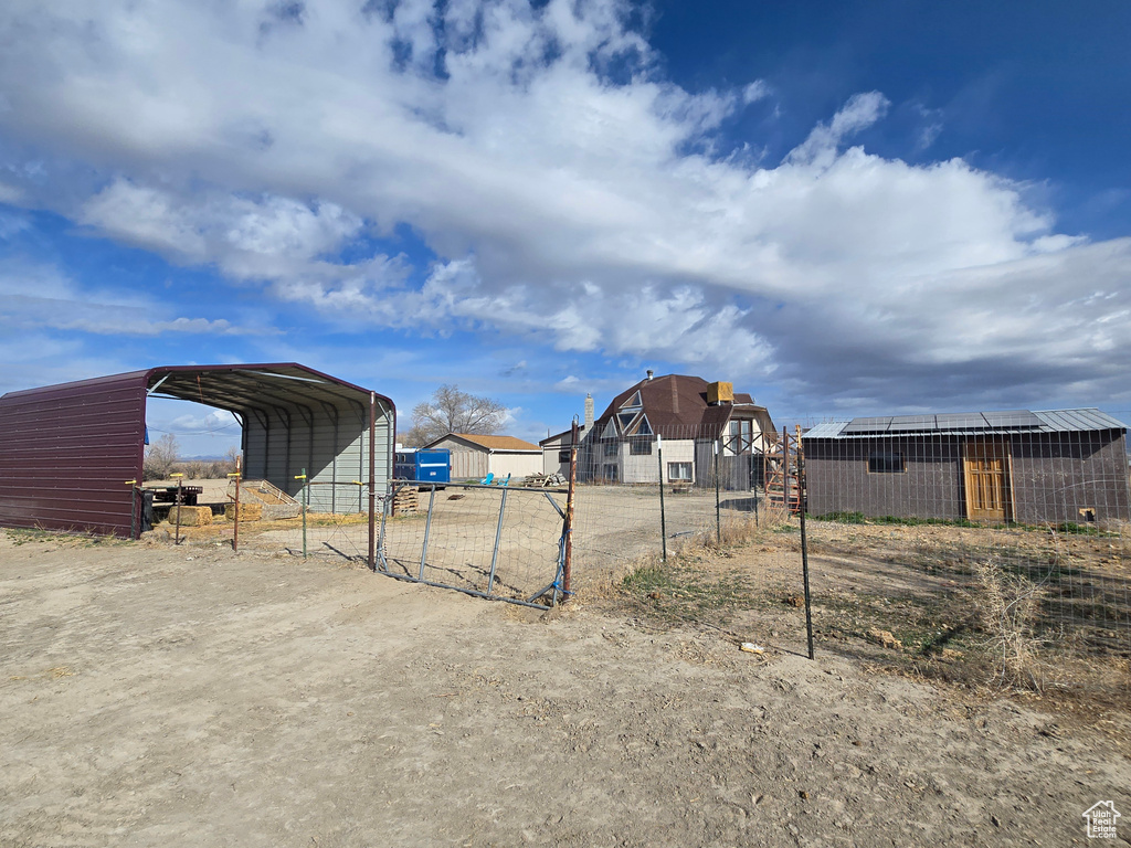 View of yard featuring a carport, an outbuilding, and fence