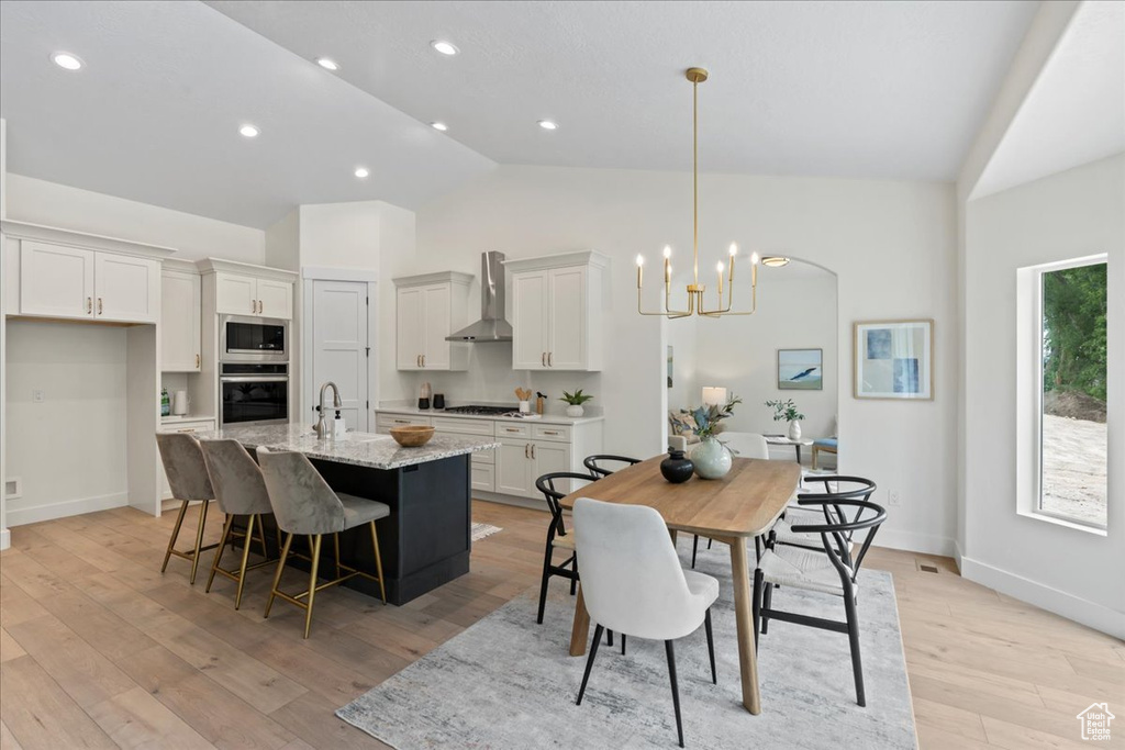 Dining area featuring a chandelier, light wood finished floors, baseboards, recessed lighting, and high vaulted ceiling