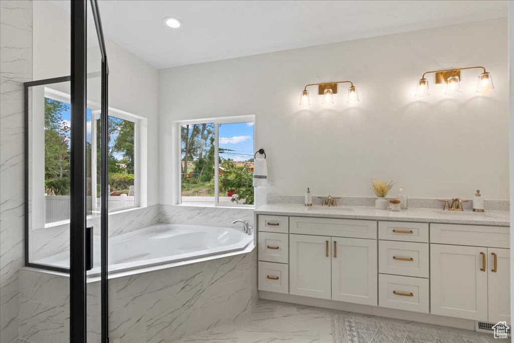 Bathroom with marble finish flooring, a garden tub, double vanity, and recessed lighting