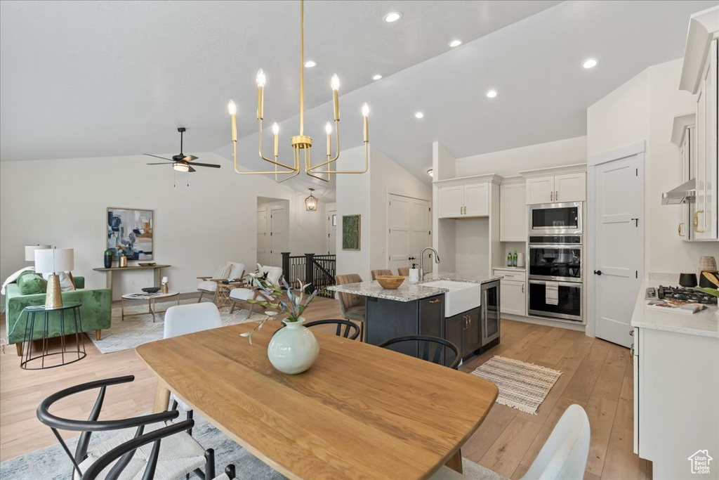 Dining space with light wood-style flooring, wine cooler, ceiling fan, high vaulted ceiling, and recessed lighting