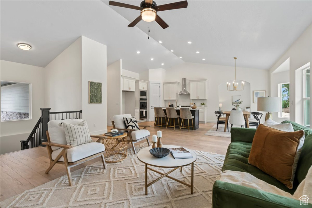 Living room with light wood-style floors, ceiling fan, recessed lighting, a chandelier, and high vaulted ceiling