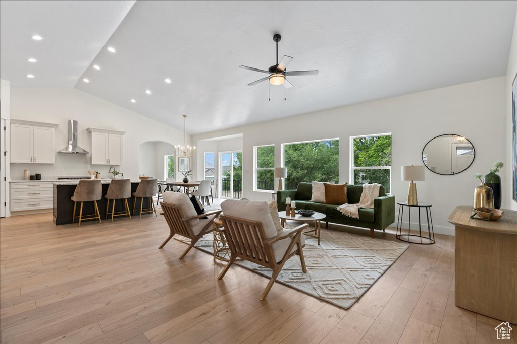 Living room featuring lofted ceiling, ceiling fan, recessed lighting, light wood-style flooring, and arched walkways