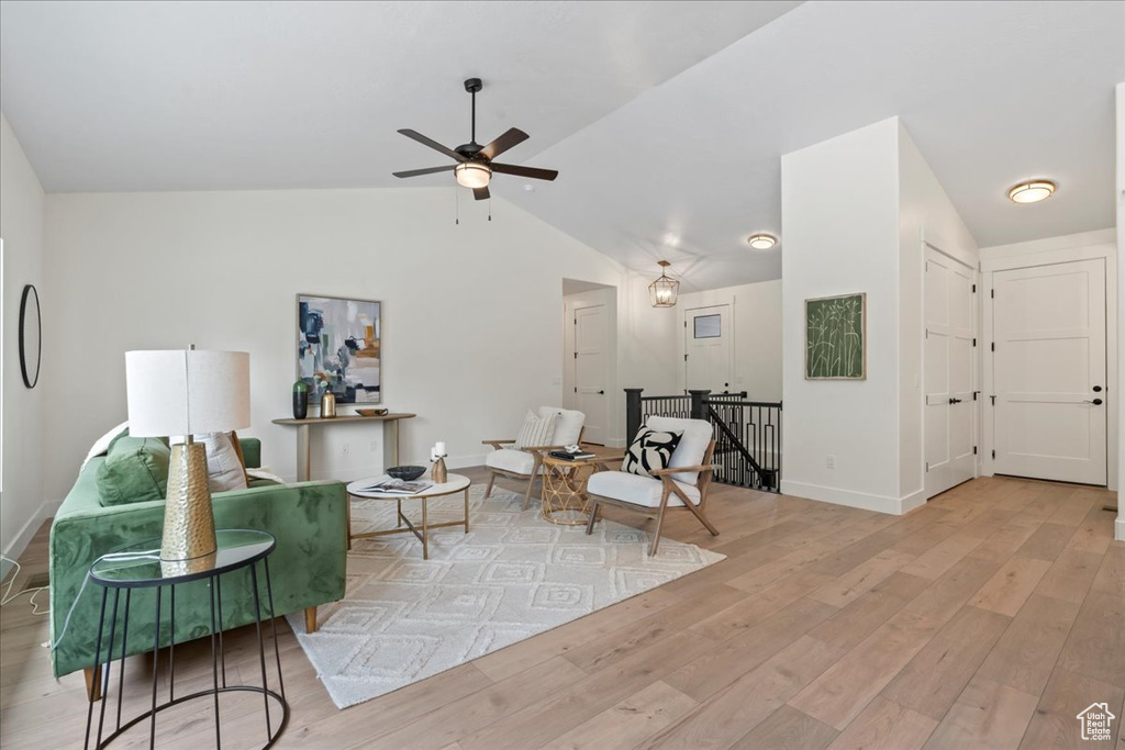 Living room with light wood-style flooring, ceiling fan, lofted ceiling, and baseboards