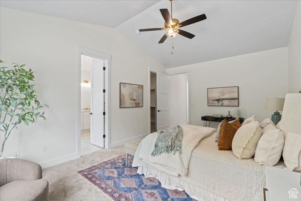 Bedroom featuring lofted ceiling, light colored carpet, baseboards, a walk in closet, and connected bathroom