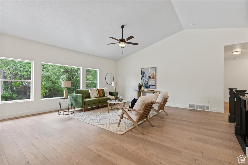 Living area featuring a ceiling fan, lofted ceiling, light wood finished floors, and baseboards