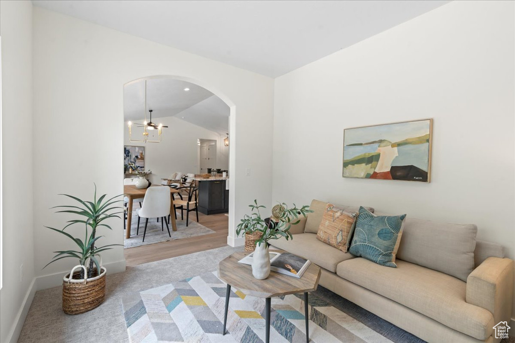 Living area featuring arched walkways, baseboards, lofted ceiling, and wood finished floors