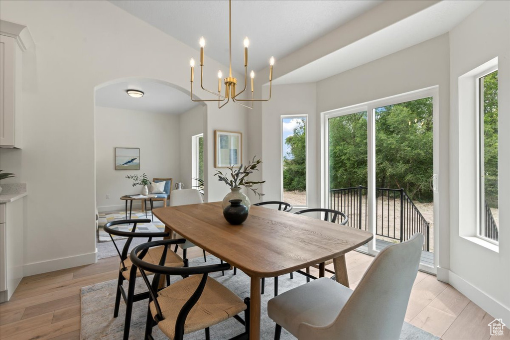 Dining space with arched walkways, baseboards, light wood-style floors, and a chandelier
