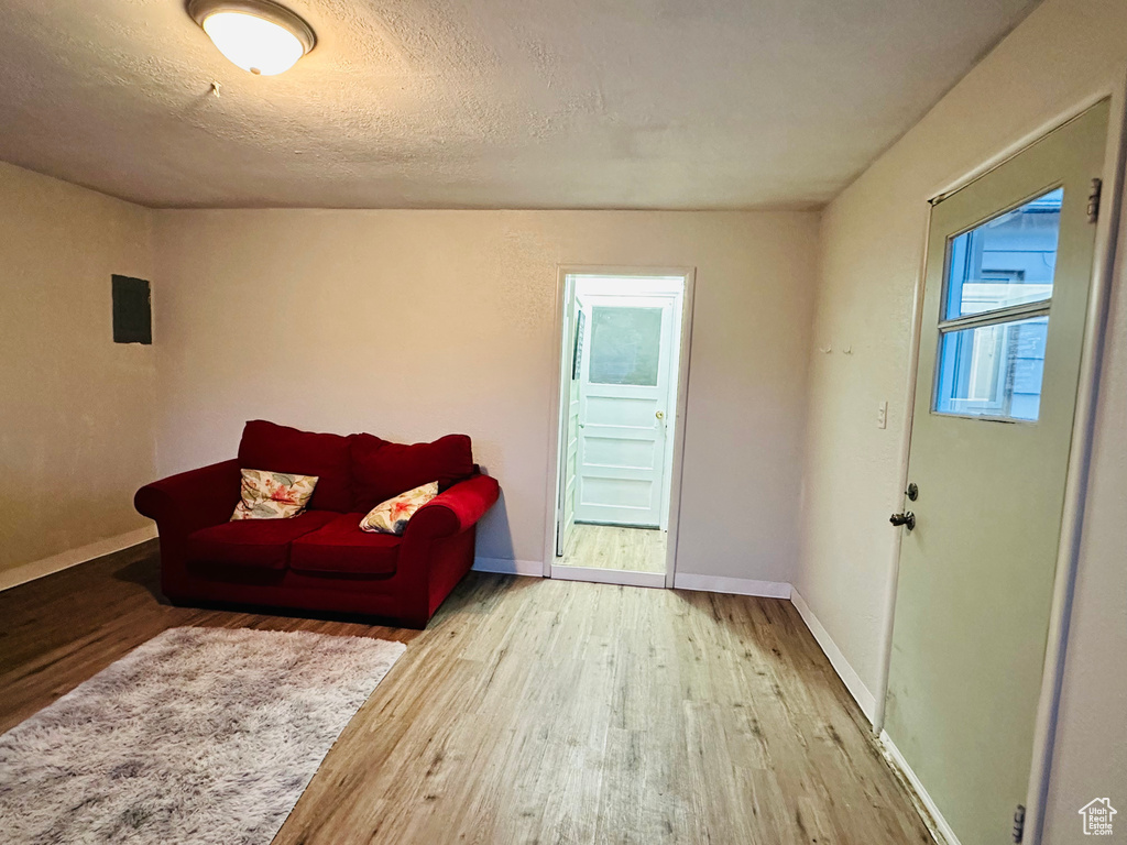 Living room featuring baseboards, a textured ceiling, and wood finished floors