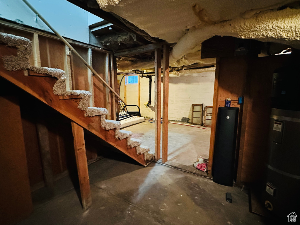 Unfinished below grade area featuring water heater and stairs