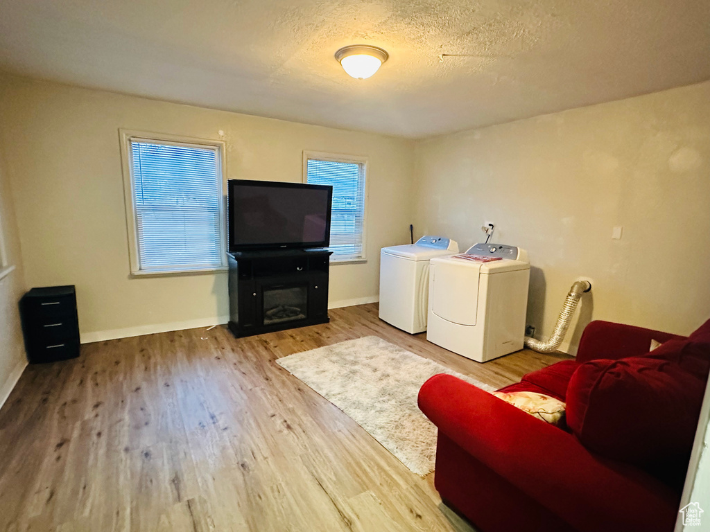 Laundry room with a textured ceiling, baseboards, a fireplace, wood finished floors, and separate washer and dryer