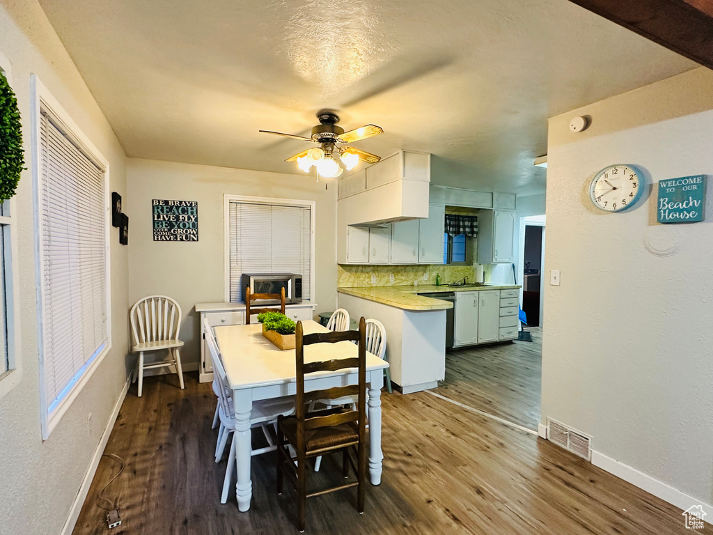 Dining room featuring dark wood finished floors, baseboards, visible vents, and ceiling fan