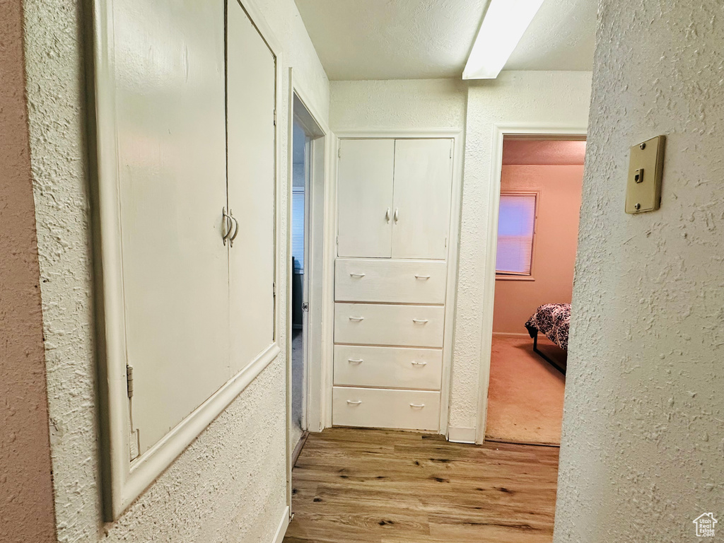 Corridor with wood finished floors and a textured wall