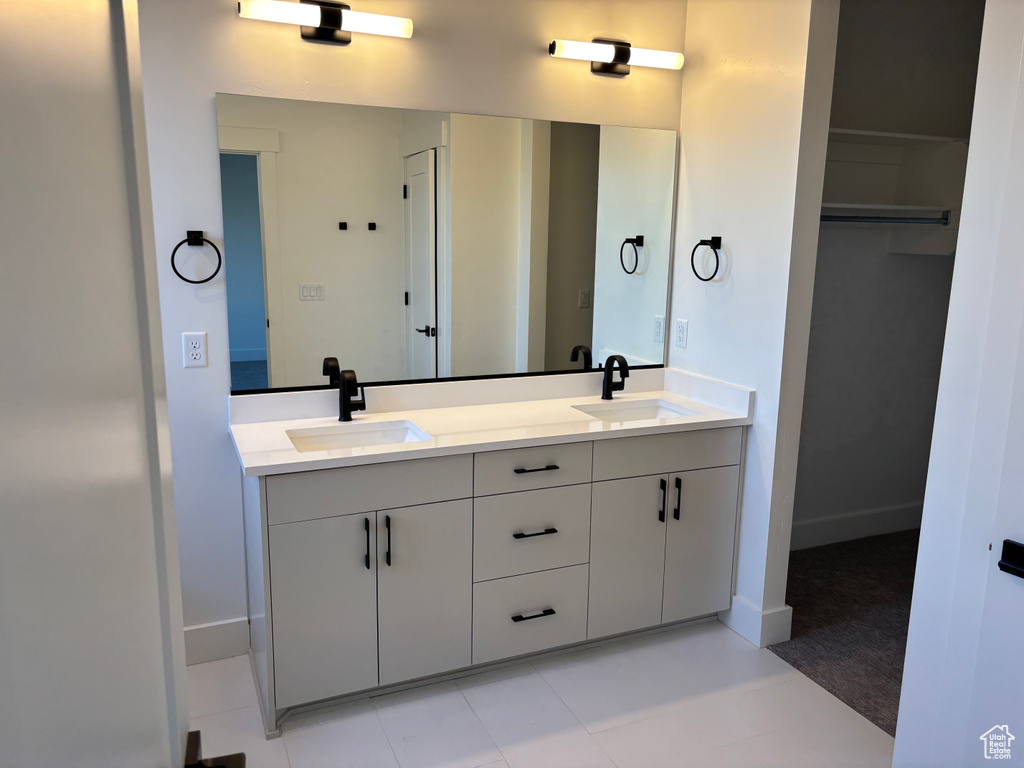 Full bath with baseboards, double vanity, and a sink