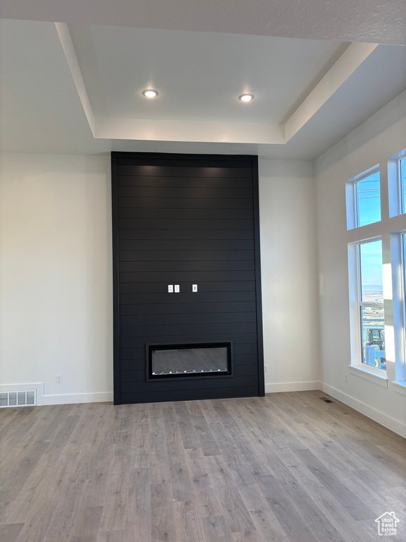 Interior details with a tray ceiling, wood finished floors, a large fireplace, baseboards, and visible vents