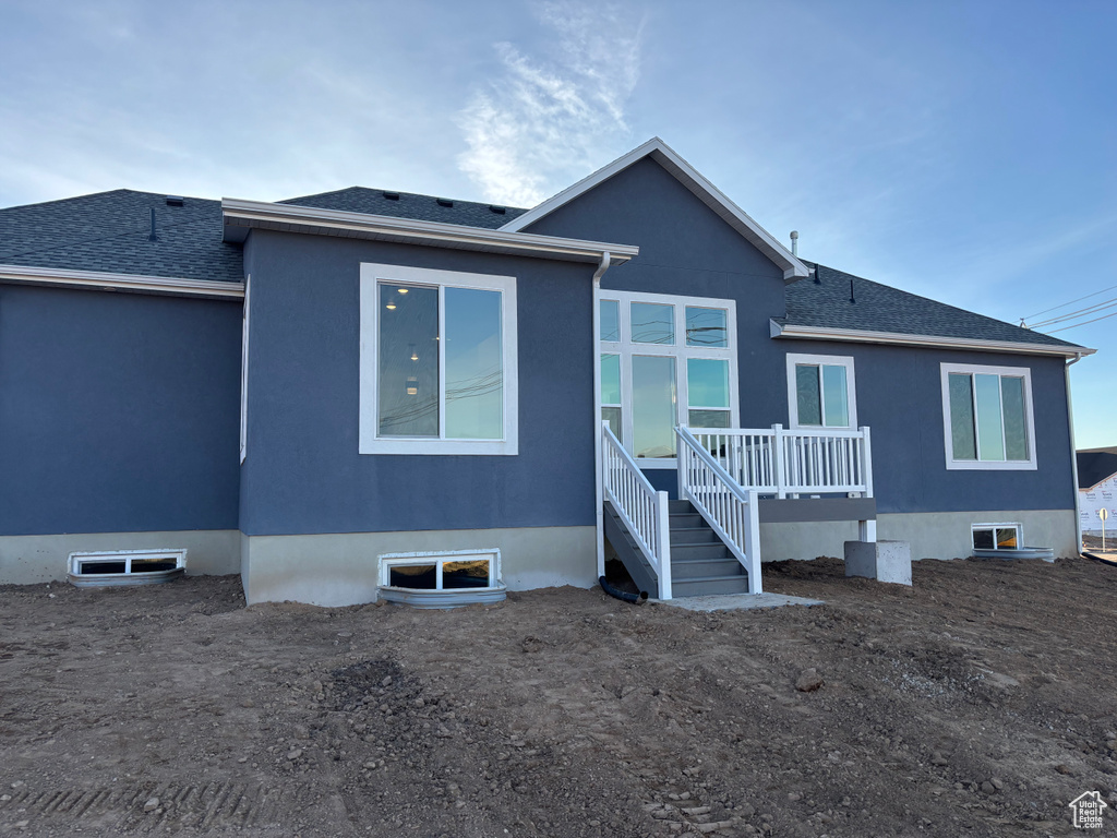 Rear view of property featuring stucco siding and roof with shingles