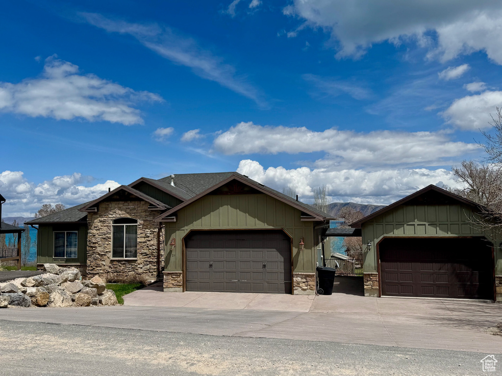 View of front of home with a garage, board and batten siding, concrete driveway, and stone siding
