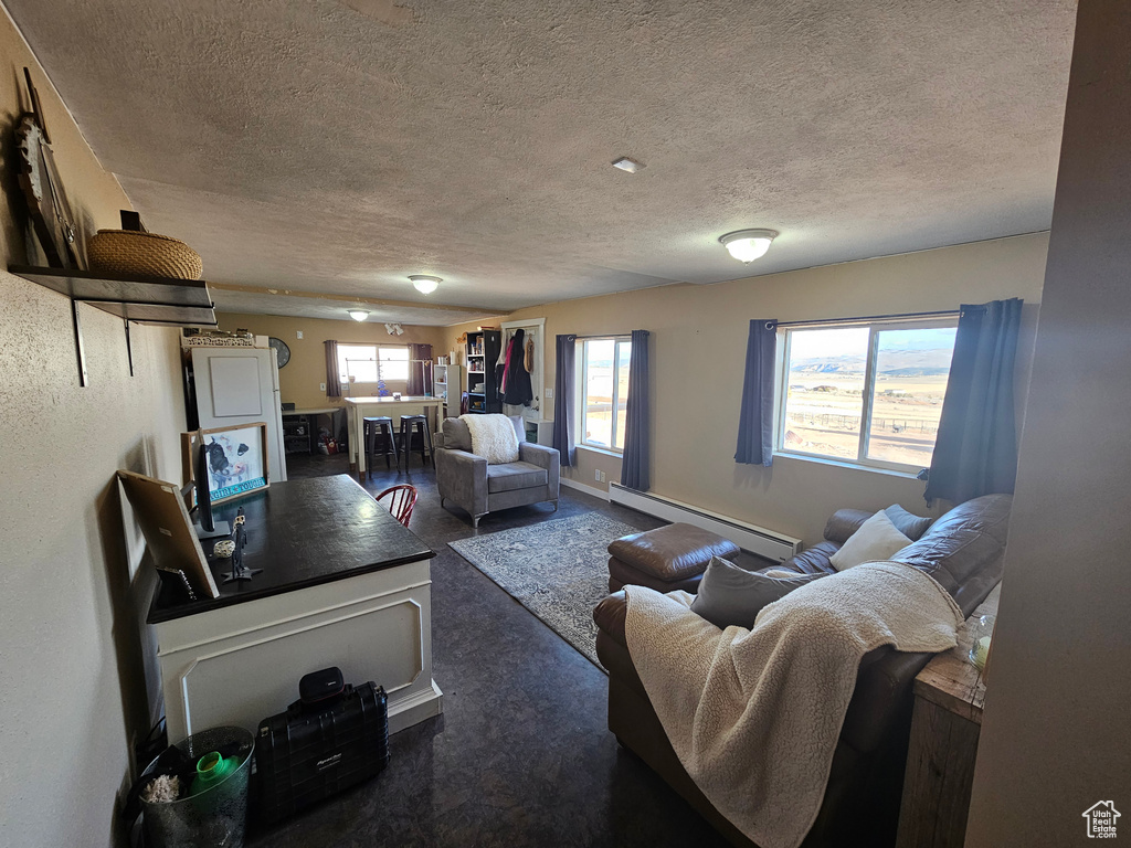 Carpeted living area featuring a textured ceiling and baseboard heating