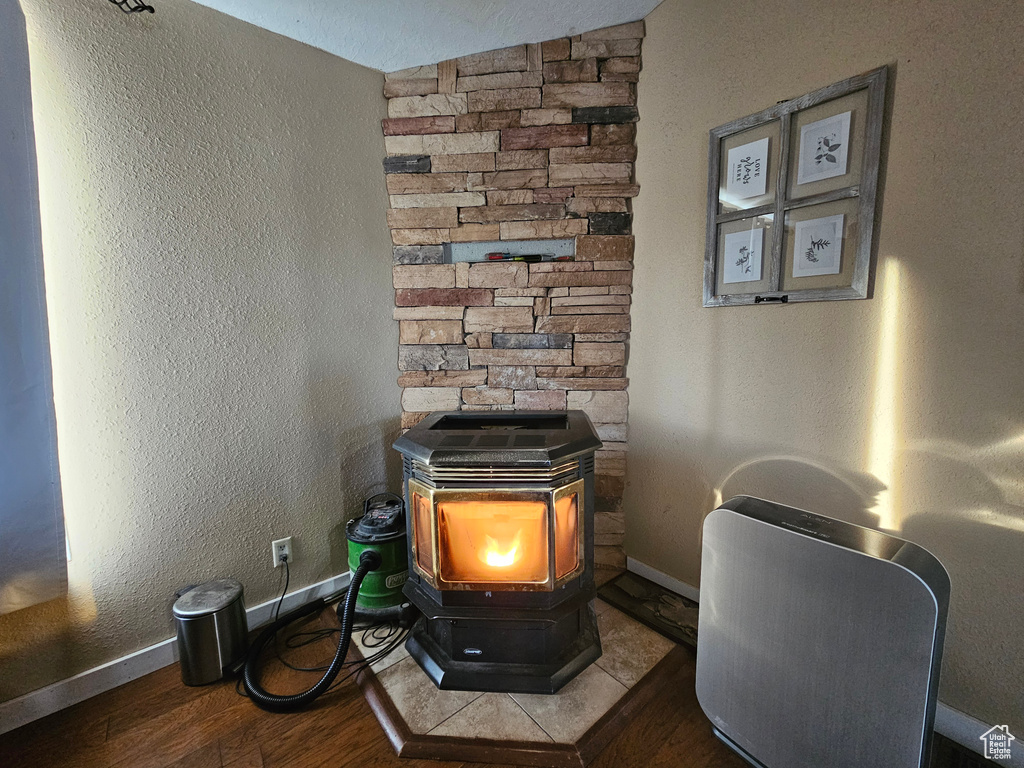 Details with baseboards, wood finished floors, a wood stove, and a textured wall