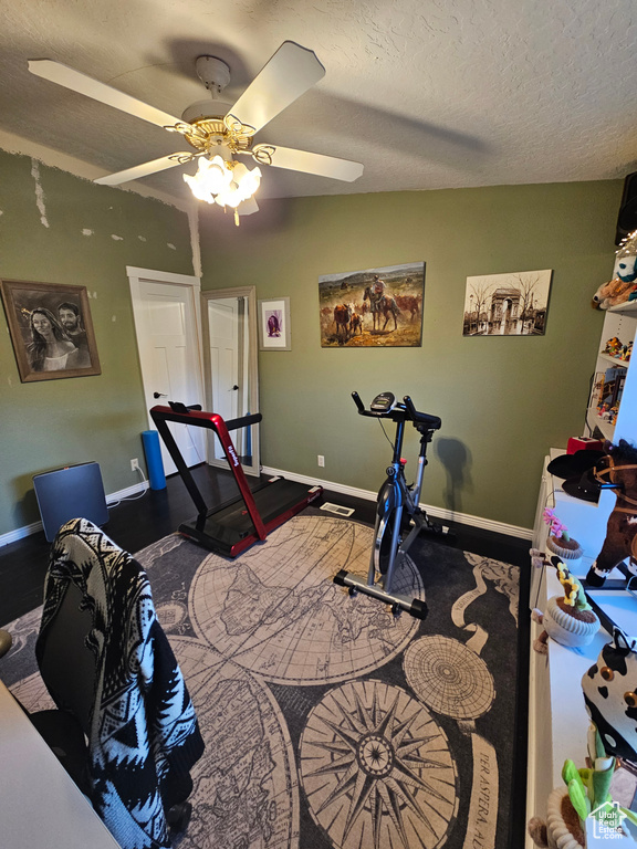 Workout area with a textured ceiling, baseboards, and ceiling fan